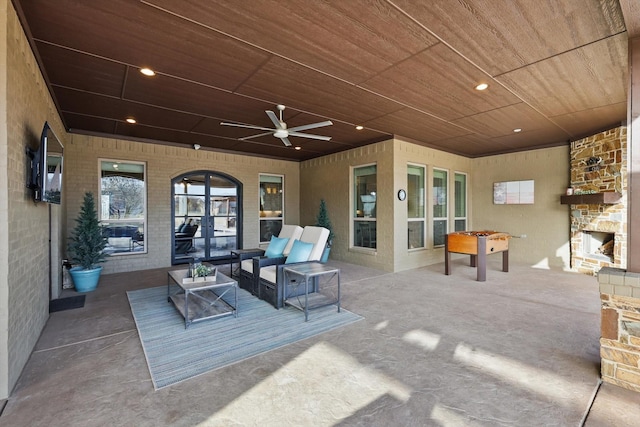 view of patio with a ceiling fan and an outdoor living space with a fireplace