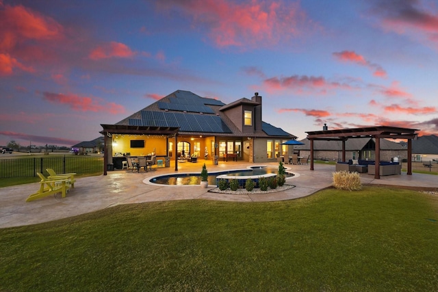 back of property with solar panels, an in ground hot tub, a yard, a pergola, and a patio area