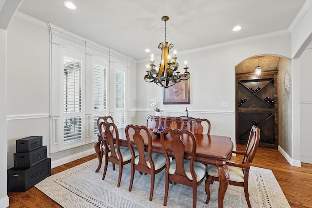 dining area with baseboards, ornamental molding, recessed lighting, wood finished floors, and arched walkways