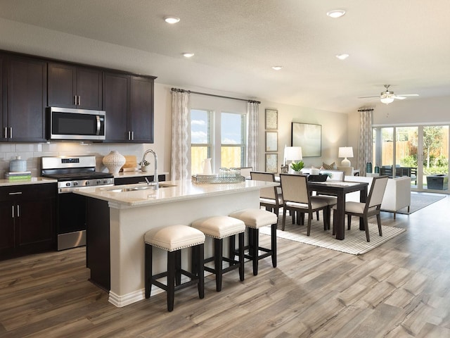 kitchen with stainless steel appliances, wood finished floors, open floor plan, and decorative backsplash