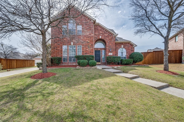 traditional-style house featuring brick siding, a front yard, and fence