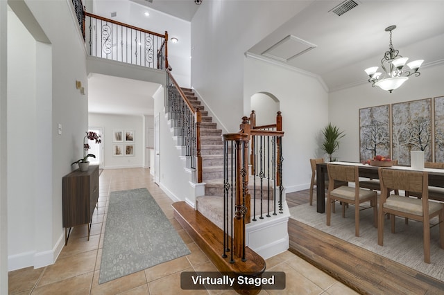 entrance foyer featuring visible vents, a high ceiling, light tile patterned flooring, baseboards, and a chandelier