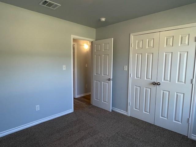 unfurnished bedroom featuring a closet, visible vents, baseboards, and carpet