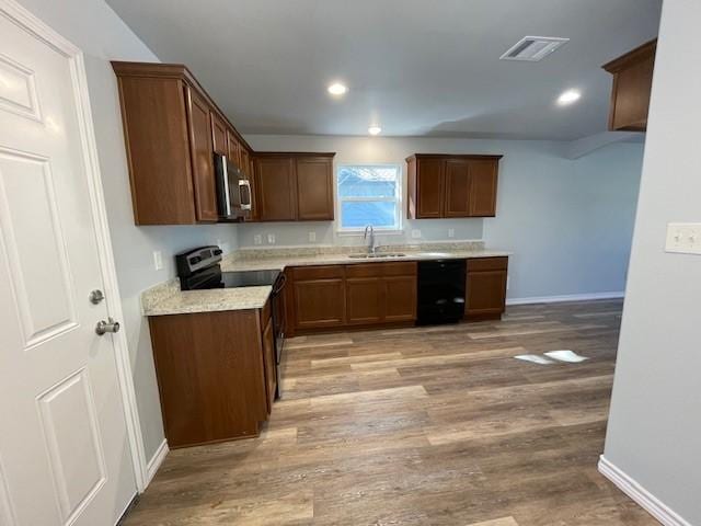kitchen with light wood-style flooring, electric stove, a sink, stainless steel microwave, and dishwasher