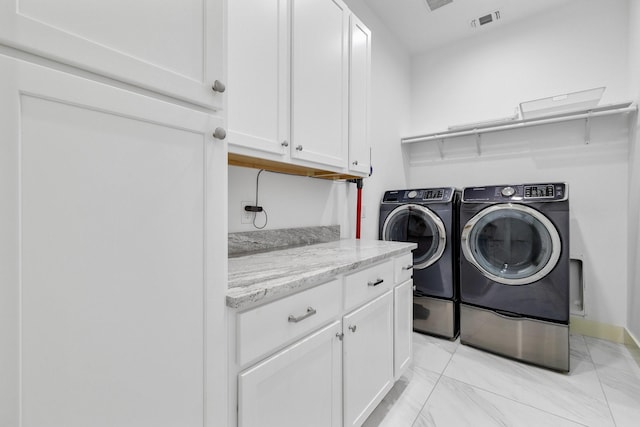 clothes washing area featuring cabinet space, washing machine and dryer, visible vents, and marble finish floor