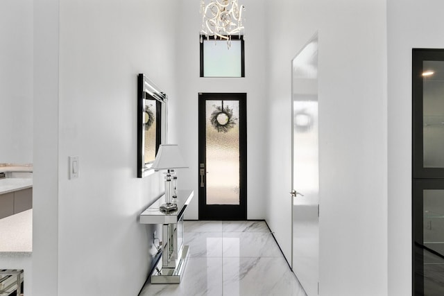 foyer entrance with marble finish floor and an inviting chandelier