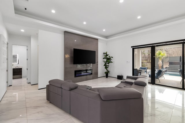 living area with a tray ceiling, recessed lighting, marble finish floor, and a large fireplace