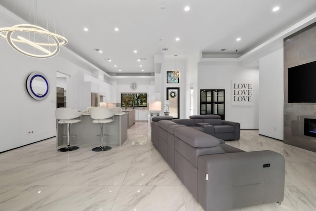 living room featuring recessed lighting, a notable chandelier, marble finish floor, and a towering ceiling