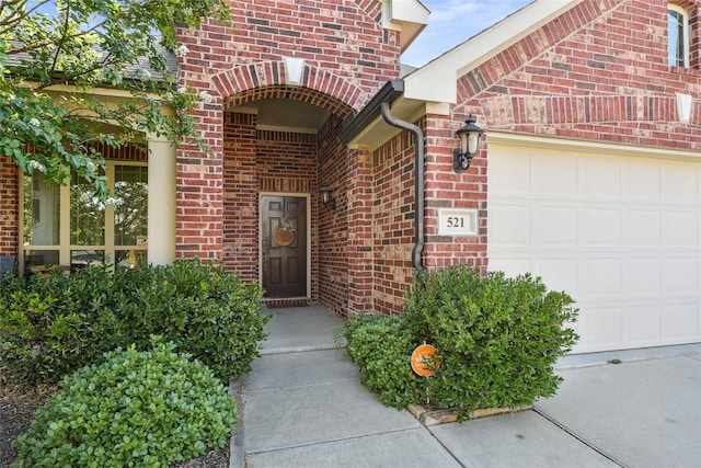 view of exterior entry featuring brick siding and an attached garage