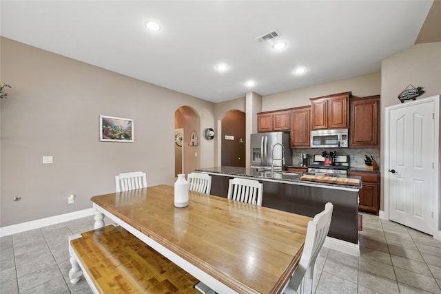 dining room with arched walkways, light tile patterned floors, baseboards, and visible vents