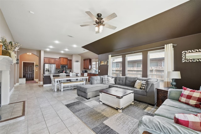 living room featuring visible vents, a ceiling fan, arched walkways, light tile patterned floors, and lofted ceiling