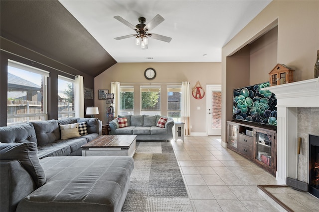 living room with a healthy amount of sunlight, light tile patterned flooring, vaulted ceiling, and a tile fireplace