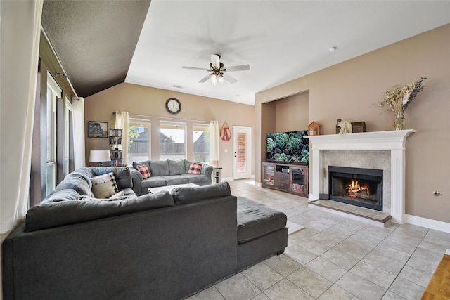 living room featuring a ceiling fan, light tile patterned floors, baseboards, vaulted ceiling, and a tile fireplace