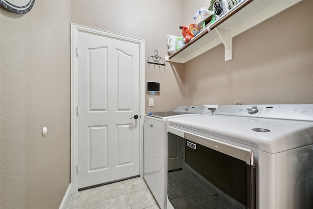 laundry area with light tile patterned floors, baseboards, laundry area, and washer and clothes dryer