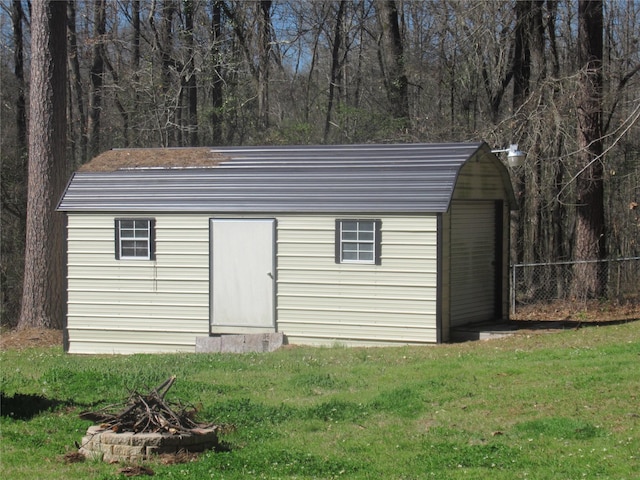 view of outbuilding with an outbuilding, fence, and an outdoor fire pit