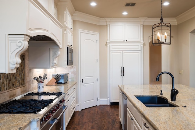 kitchen with built in appliances, ornamental molding, visible vents, and a sink