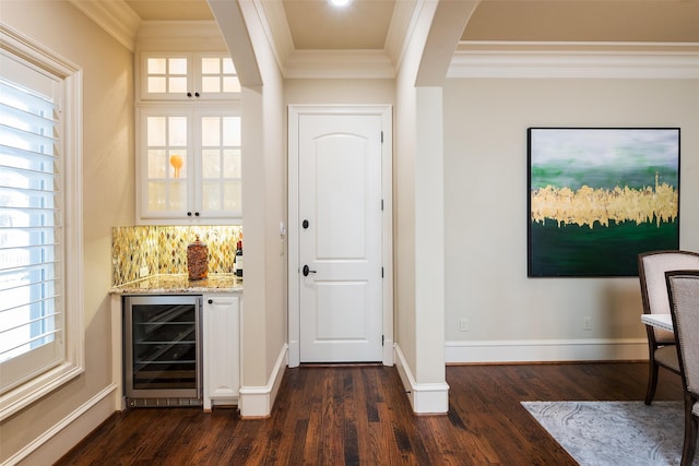 bar featuring crown molding, baseboards, beverage cooler, a dry bar, and dark wood-style floors