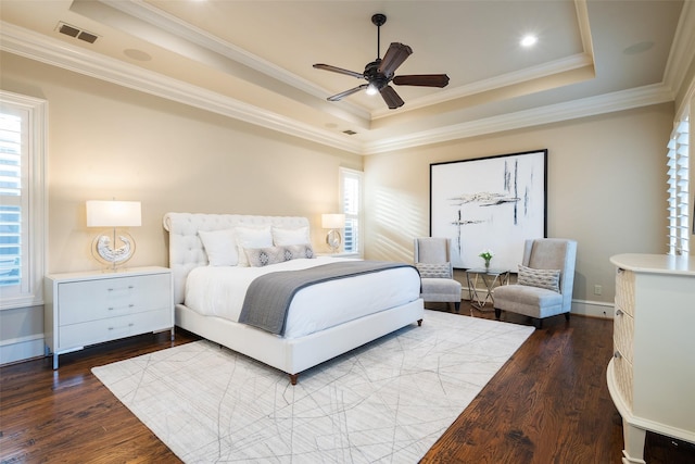 bedroom featuring a tray ceiling, visible vents, dark wood-style floors, and crown molding