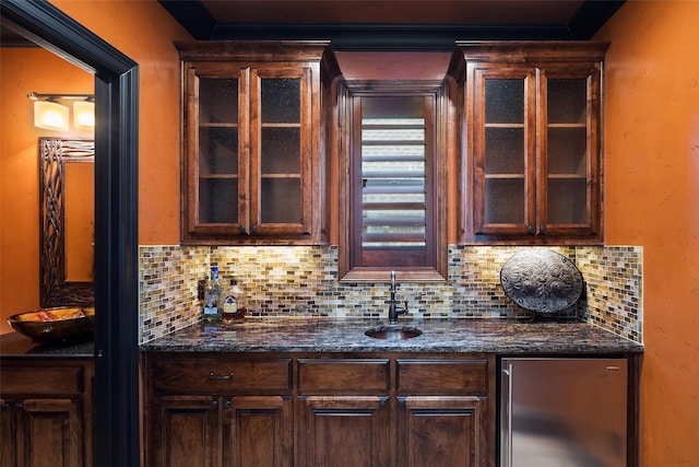 bar featuring a sink, stainless steel fridge, backsplash, and wet bar