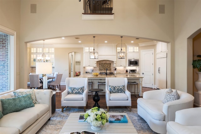 living area featuring wood finished floors, recessed lighting, arched walkways, a towering ceiling, and a notable chandelier