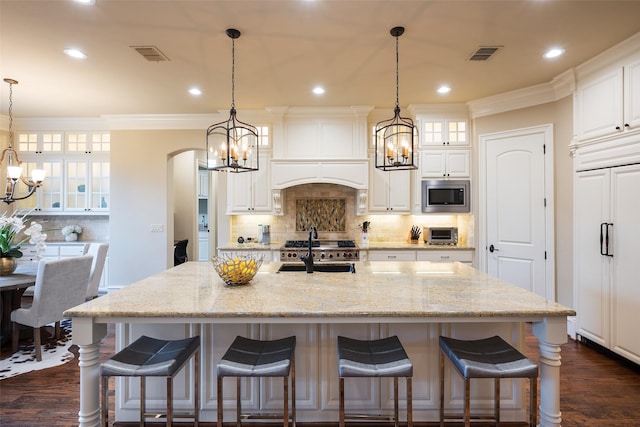 kitchen with visible vents, an inviting chandelier, arched walkways, ornamental molding, and built in appliances