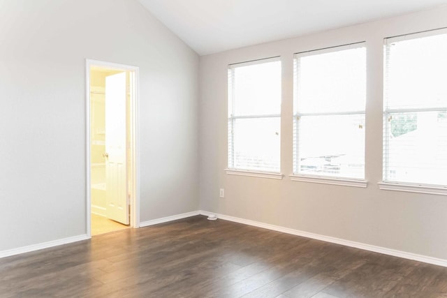 empty room featuring baseboards, dark wood finished floors, and vaulted ceiling