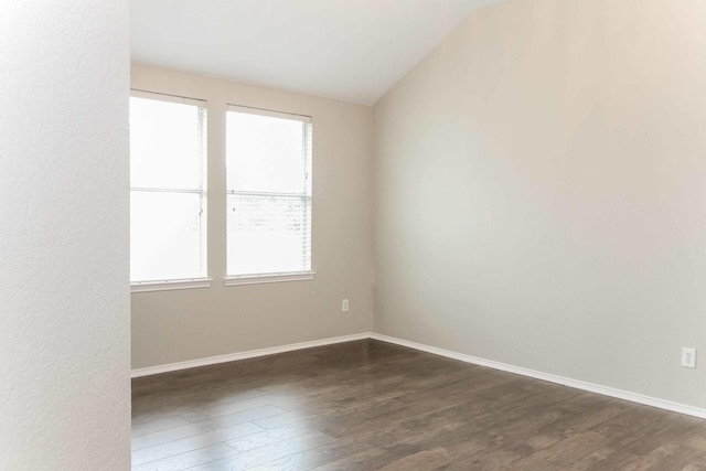 spare room with baseboards and dark wood-type flooring