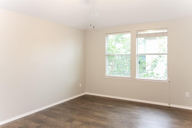 empty room with baseboards and dark wood finished floors