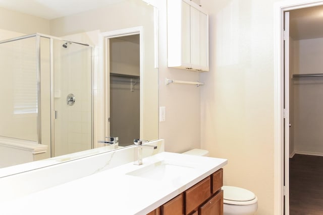 full bathroom featuring a shower stall, vanity, toilet, and a walk in closet