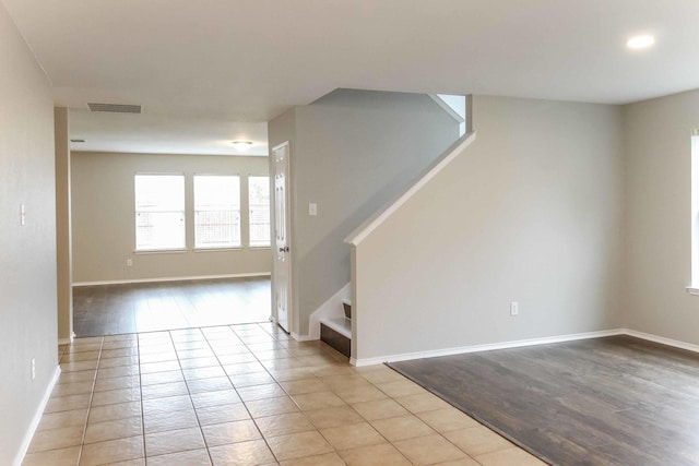 unfurnished room with light tile patterned floors, stairway, baseboards, and visible vents