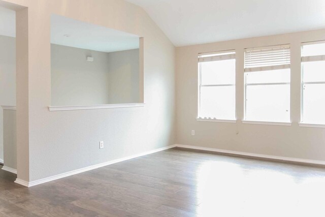 unfurnished room featuring baseboards, lofted ceiling, and wood finished floors