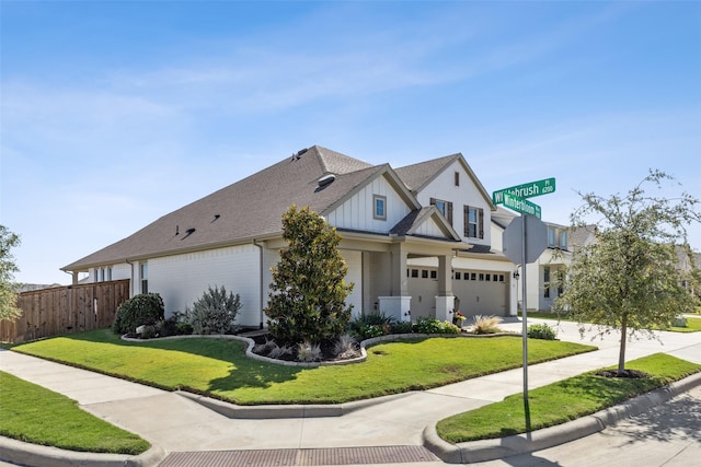 view of front facade with a front yard, concrete driveway, fence, and board and batten siding