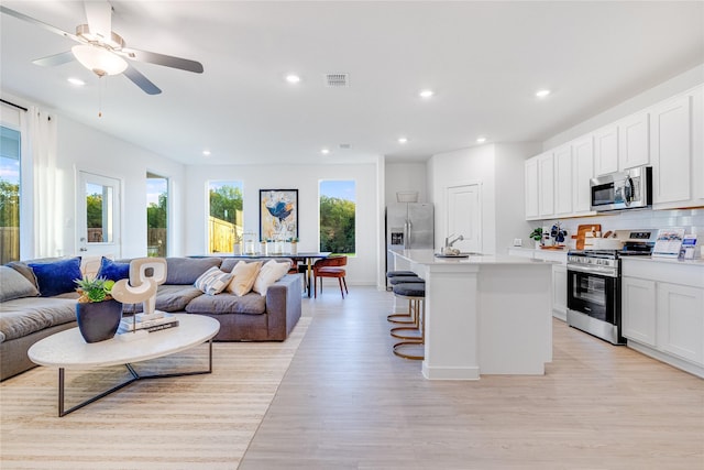 interior space featuring visible vents, open floor plan, a breakfast bar area, light wood-style flooring, and appliances with stainless steel finishes