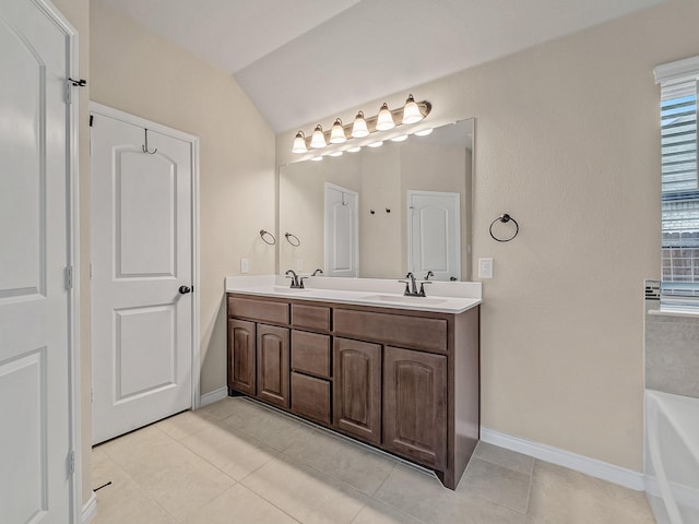 bathroom featuring vaulted ceiling, a bathtub, double vanity, and a sink