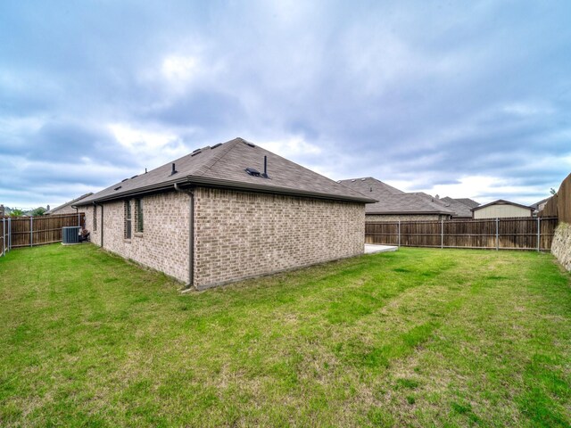 rear view of house featuring a yard, central air condition unit, brick siding, and a fenced backyard