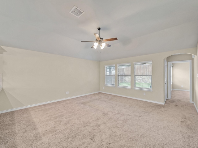 spare room with lofted ceiling, light colored carpet, visible vents, and arched walkways