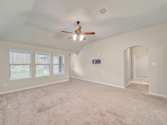 empty room featuring visible vents, light carpet, a ceiling fan, arched walkways, and lofted ceiling