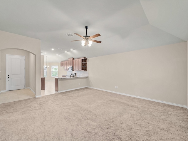 unfurnished living room with visible vents, light carpet, lofted ceiling, baseboards, and ceiling fan