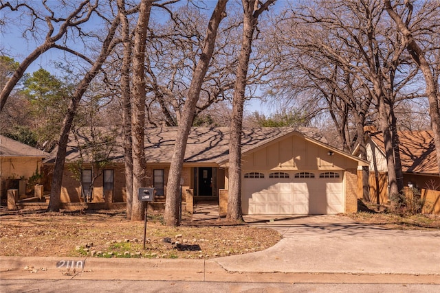 mid-century inspired home with board and batten siding, brick siding, a garage, and driveway