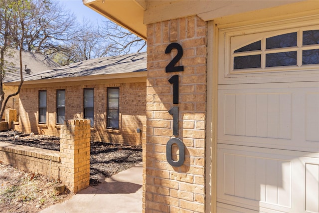 doorway to property with brick siding and a shingled roof