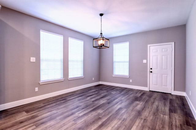 interior space with an inviting chandelier, dark wood-type flooring, and baseboards