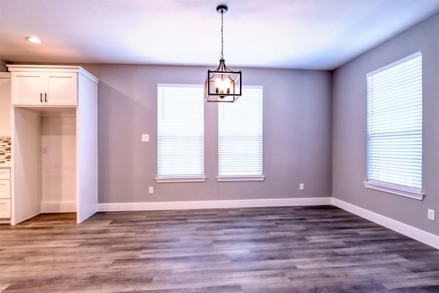 unfurnished dining area with a wealth of natural light, dark wood-style floors, and baseboards