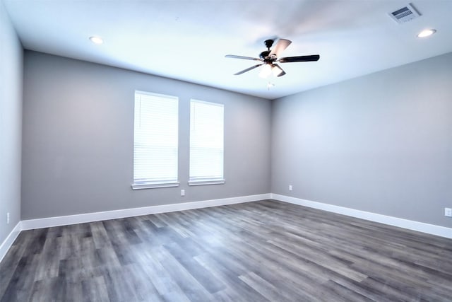 unfurnished room featuring visible vents, baseboards, and dark wood-style floors