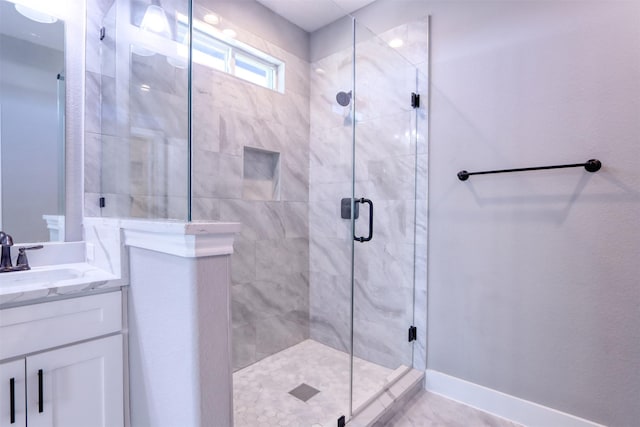 full bath with vanity, a shower stall, and baseboards