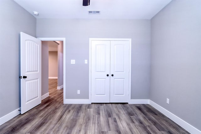 unfurnished bedroom featuring a ceiling fan, wood finished floors, visible vents, baseboards, and a closet