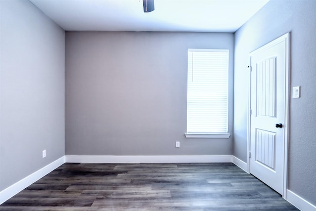 spare room with baseboards and dark wood-style flooring