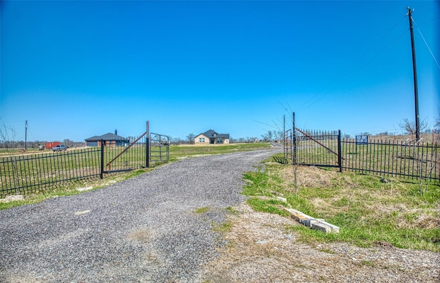 view of road featuring a gated entry, a rural view, and driveway