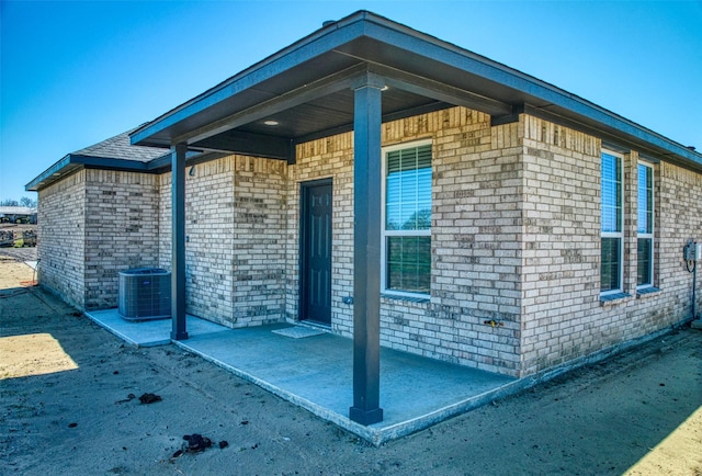 view of side of property featuring central air condition unit and brick siding