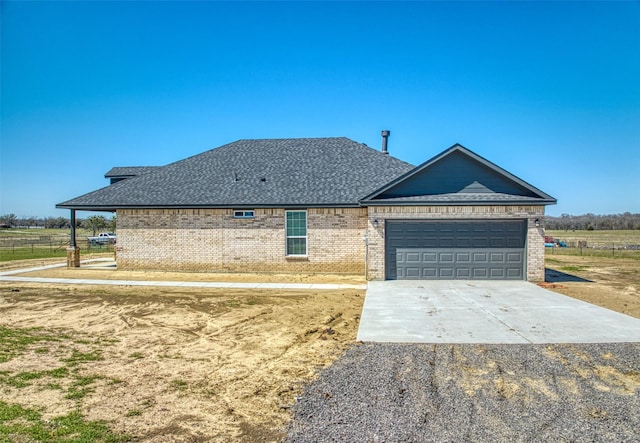 view of front of property featuring a garage, brick siding, roof with shingles, and driveway