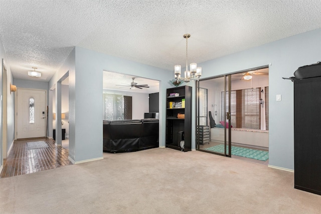 interior space featuring ceiling fan with notable chandelier, a textured ceiling, and baseboards